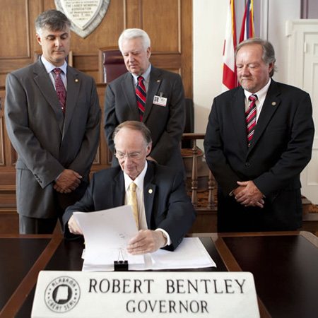 Governor Bentley signs the act into law while Scott Beason, Kerry Rich and Micky Hammon look on